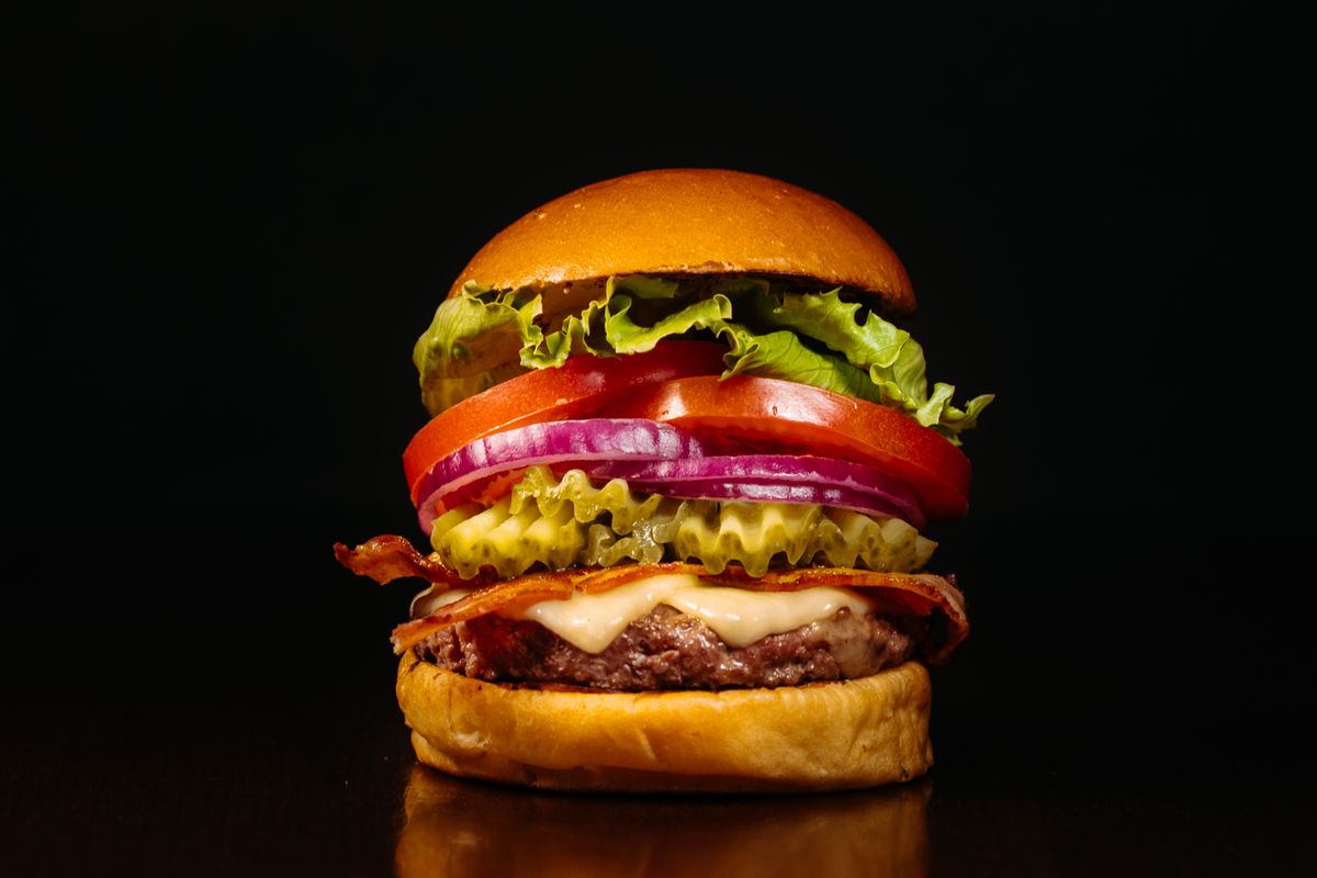 Photographie illustrative d’un burger généreux au fromage et aux légumes